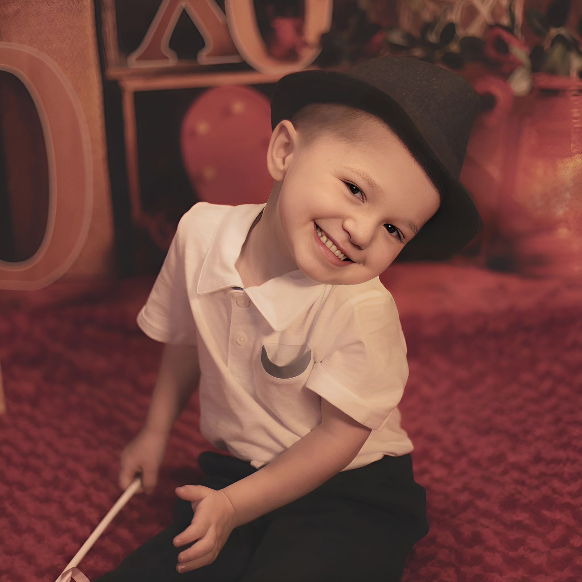 A little boy wearing a hat and holding a wand