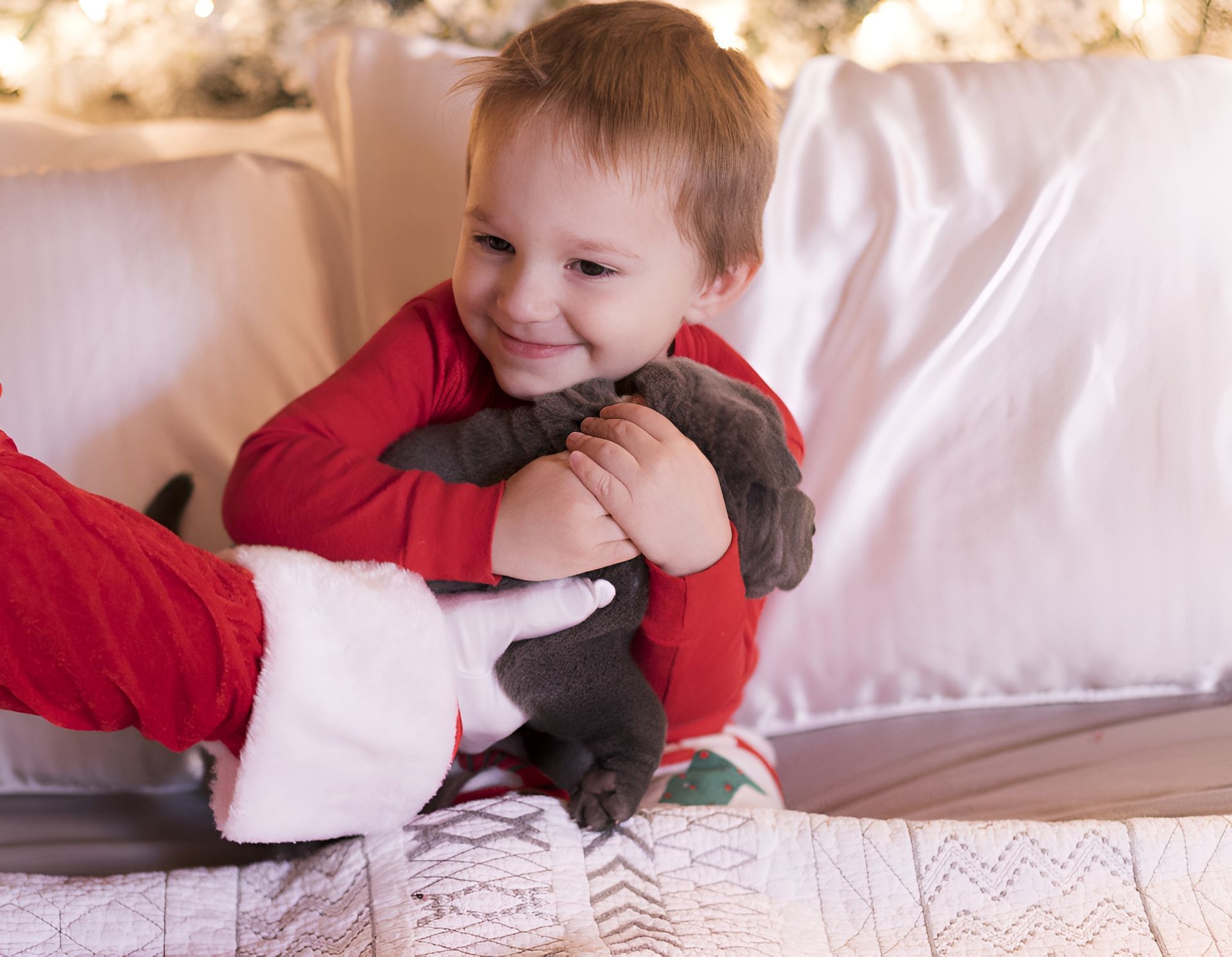 A little boy is sitting on a bed holding a stuffed animal.