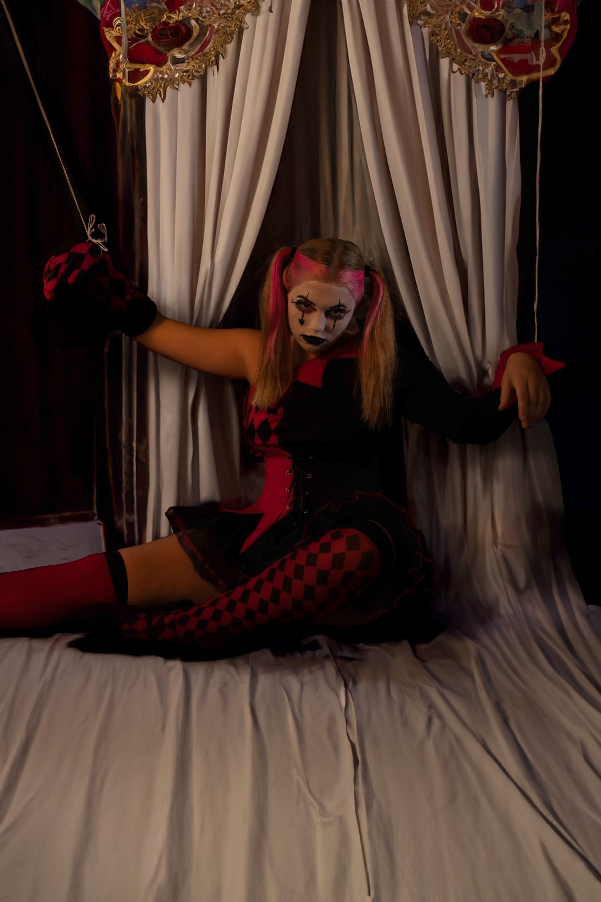 A woman in a clown costume is sitting on a bed.