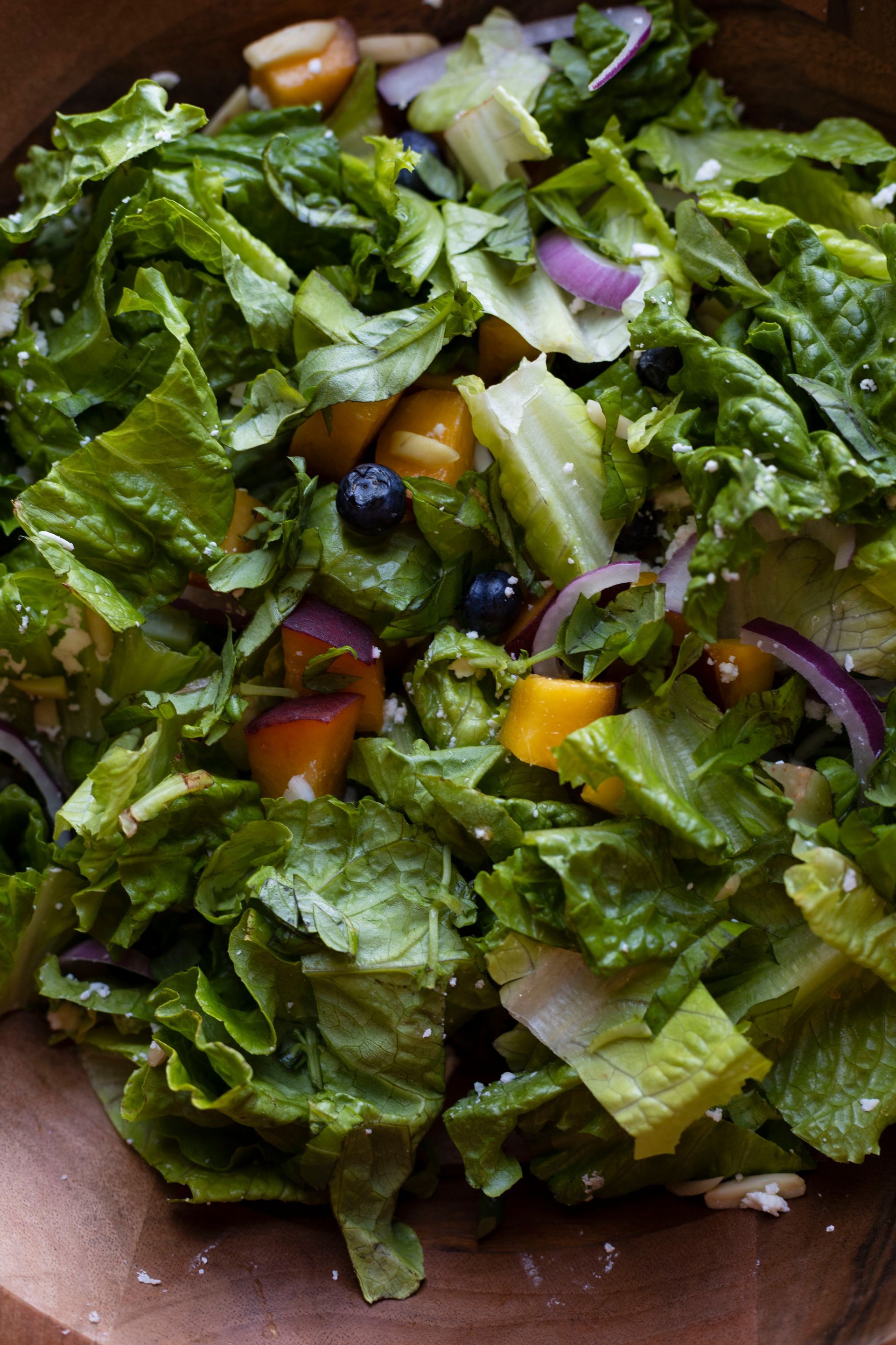 A close up of a salad in a wooden bowl.