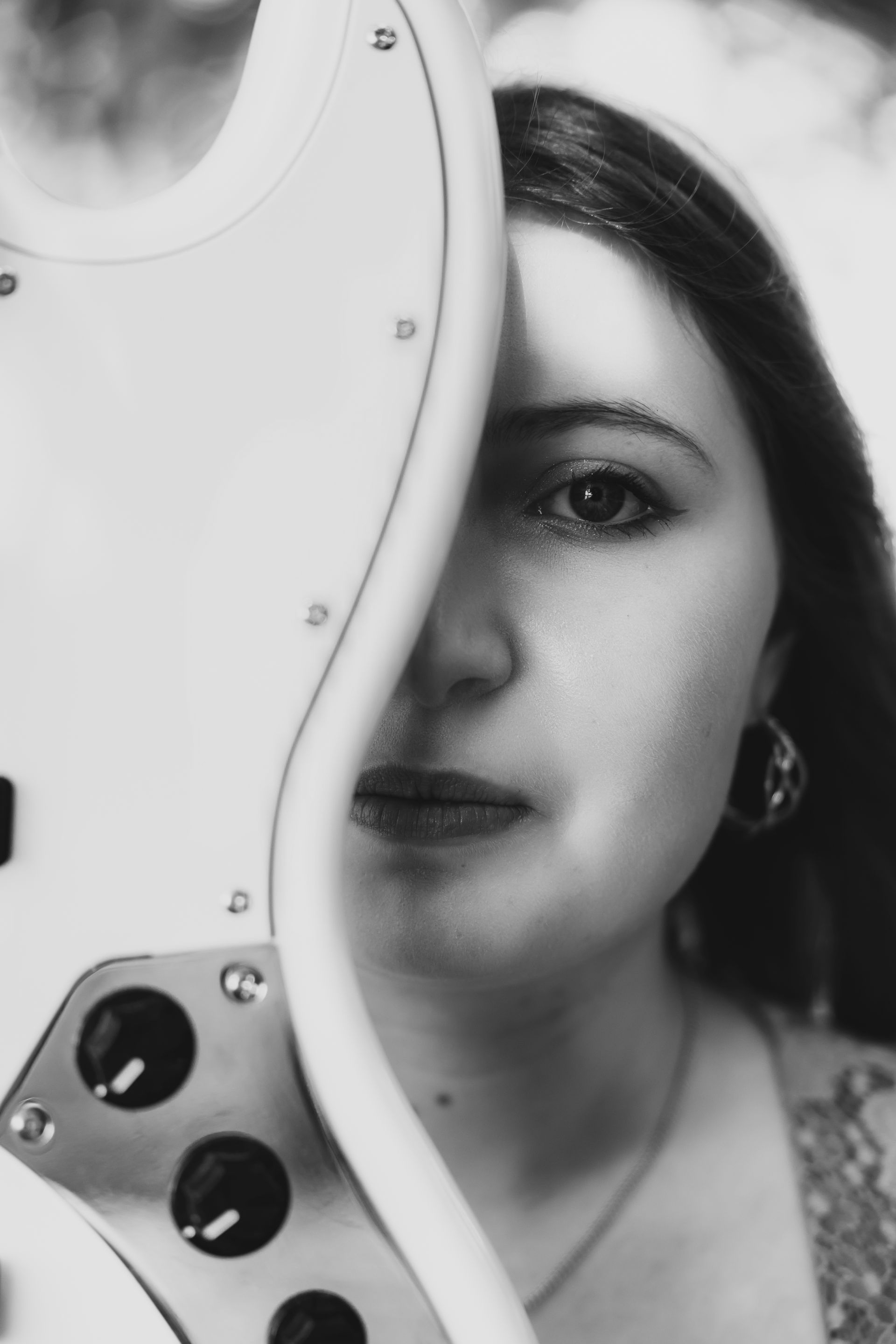 A woman is holding a guitar in front of her face