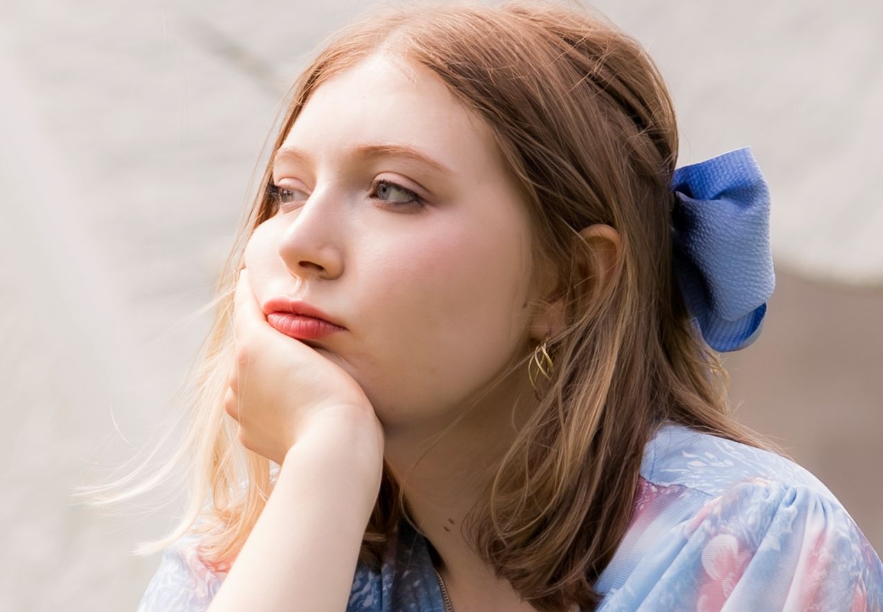 A close up of a woman 's face with her hand on her chin.