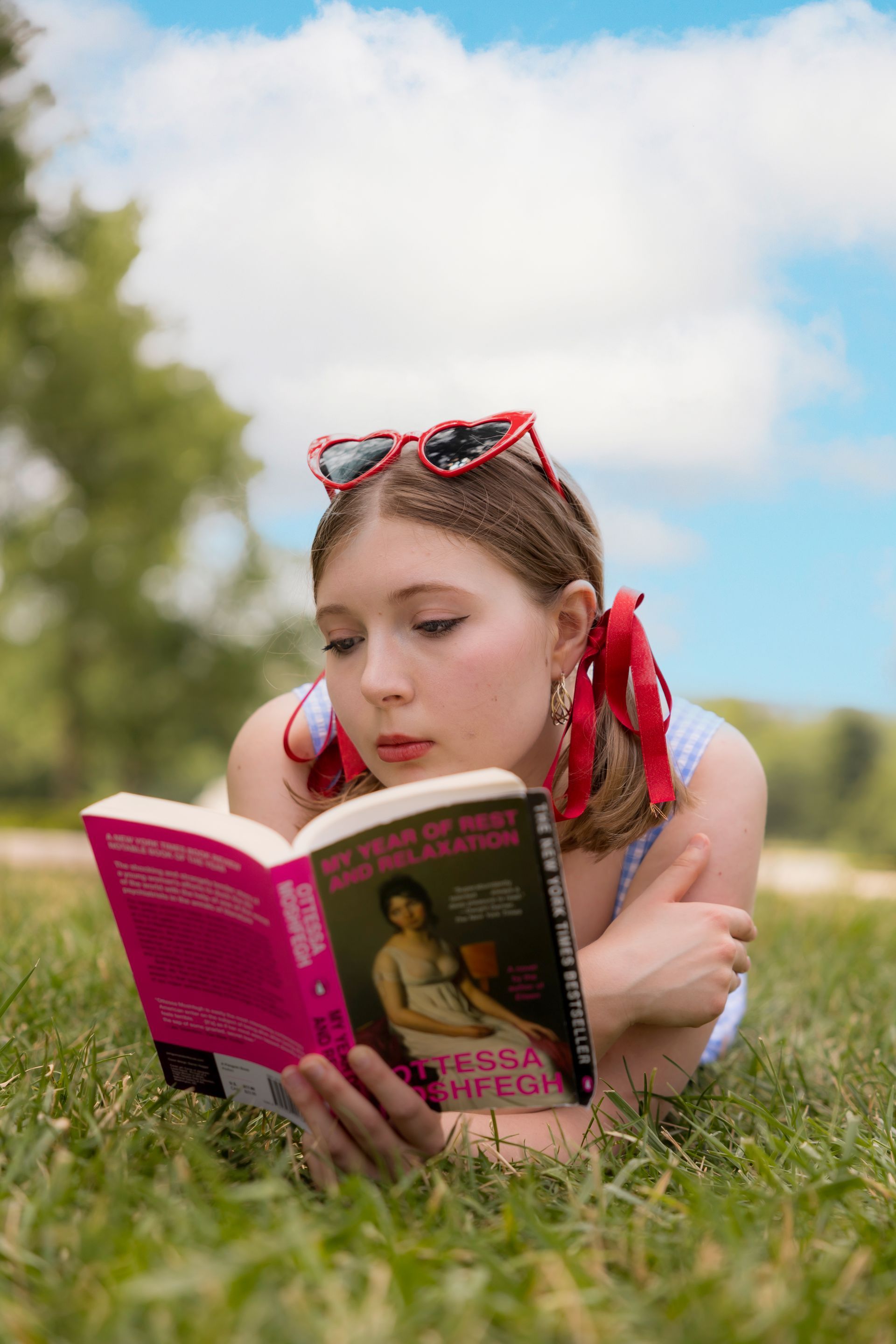 A woman is laying in the grass reading a book.