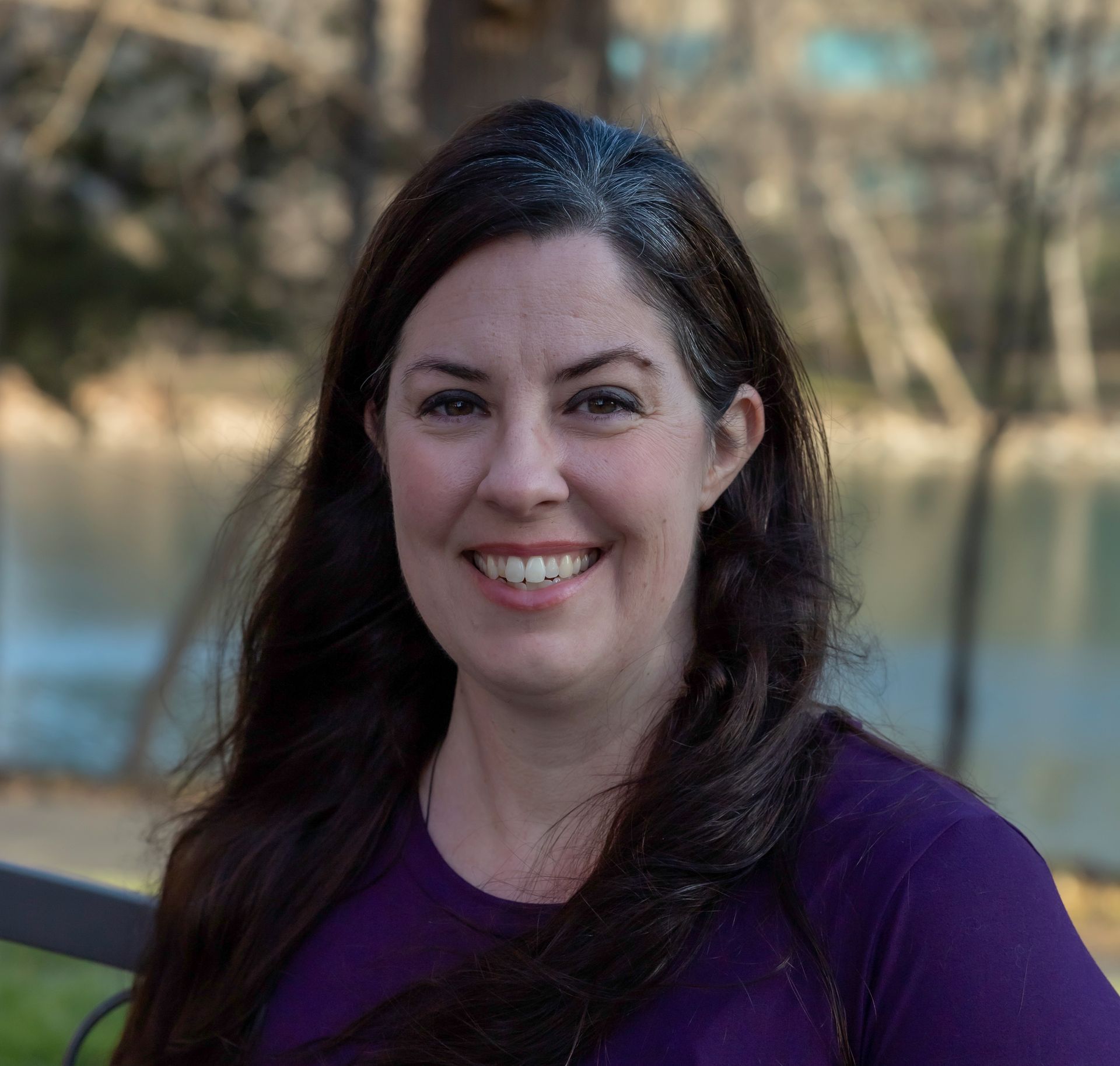 A woman in a purple shirt is smiling for the camera.