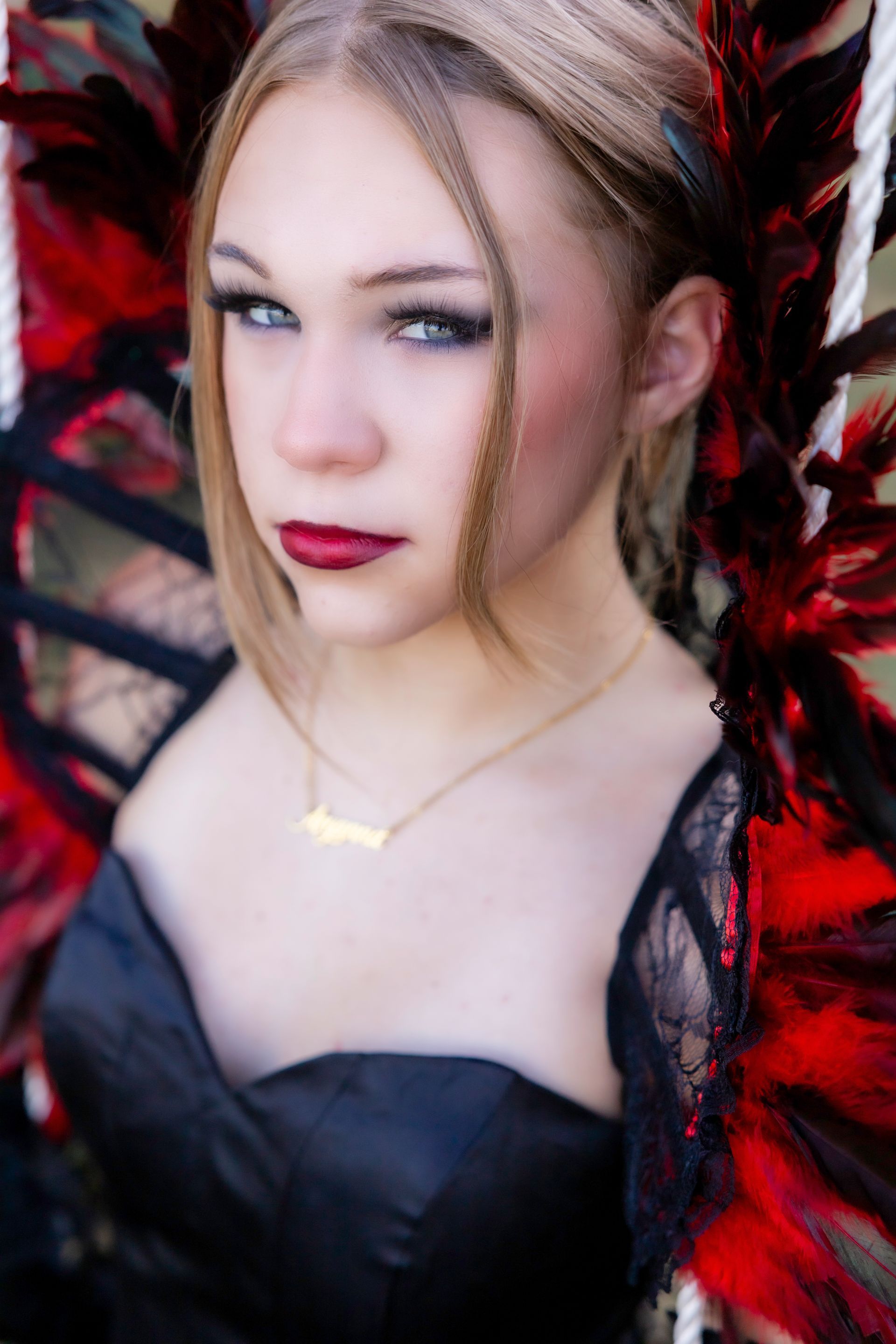 A woman wearing a black dress and red feathers is looking at the camera.