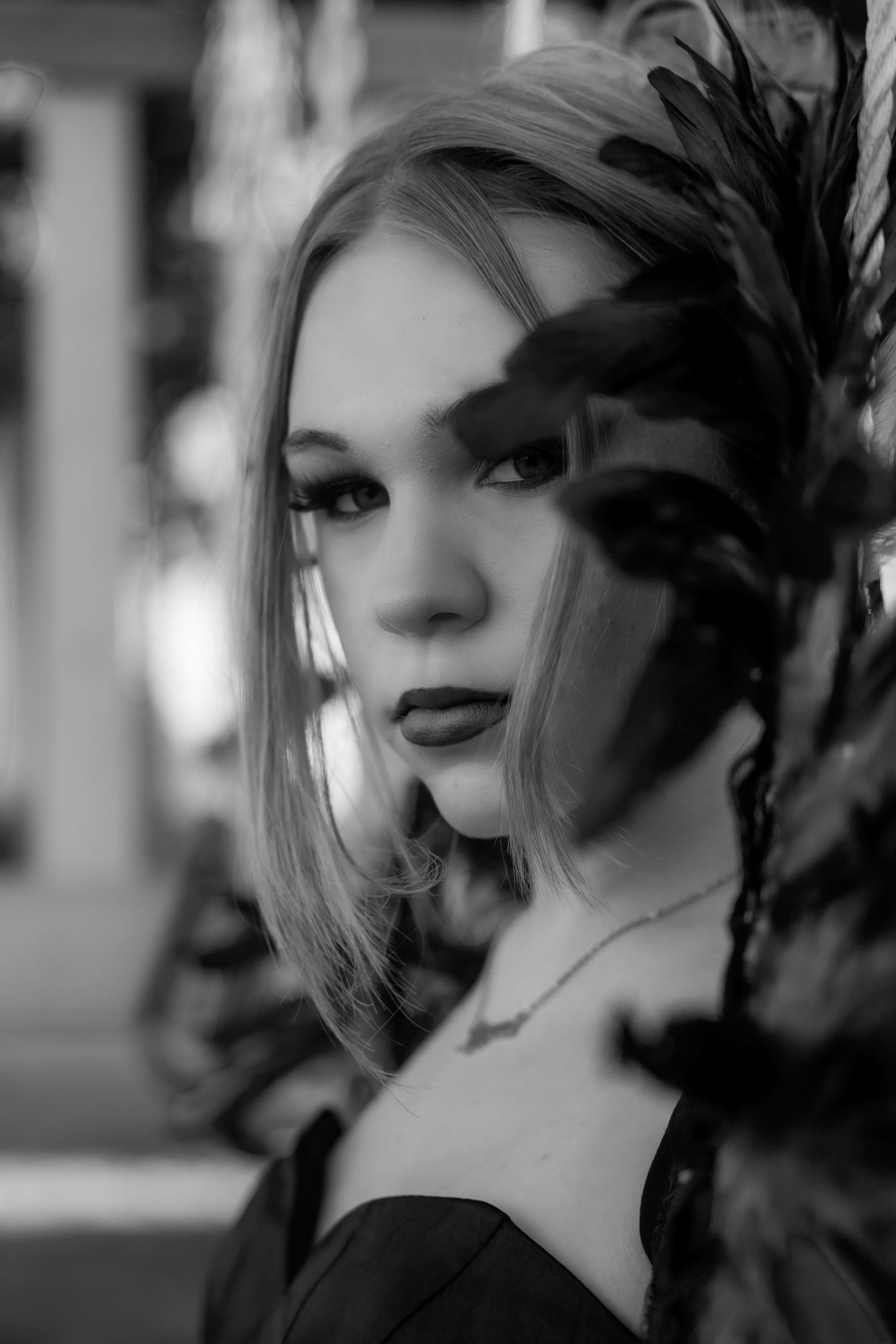 A black and white photo of a woman with feathers in her hair.