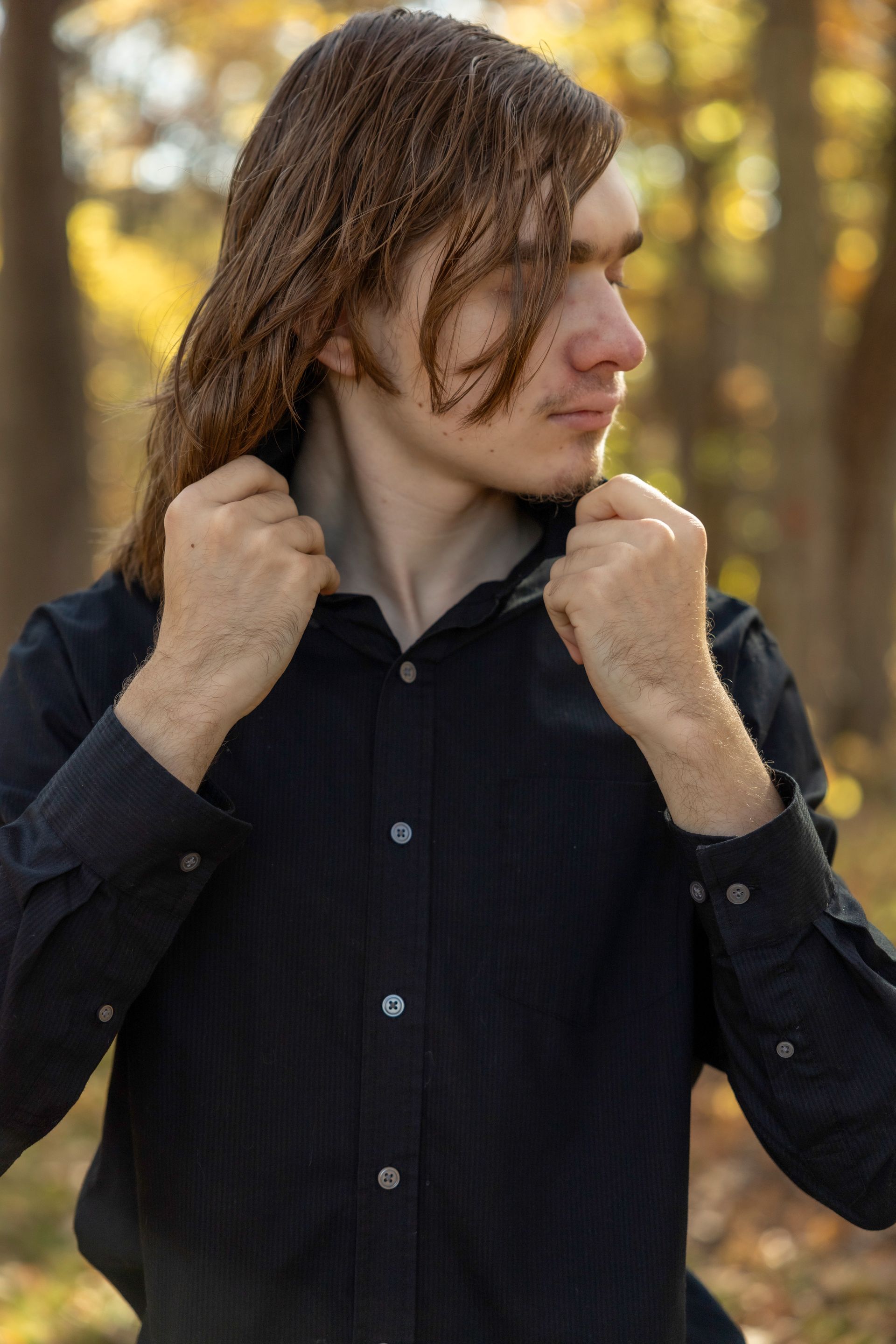 A young man with long hair is wearing a black shirt.
