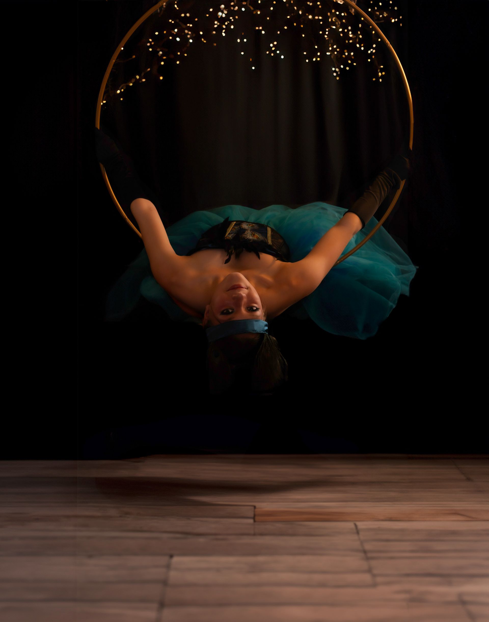 A woman is hanging upside down on an aerial hoop.