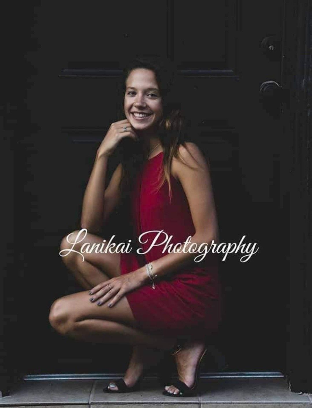 A woman in a red dress is kneeling down in front of a door.