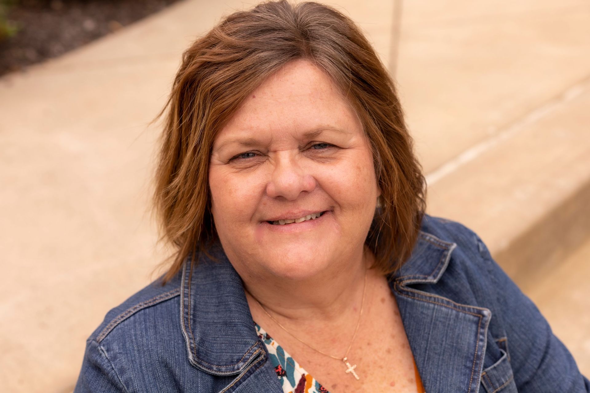 A woman in a denim jacket is smiling for the camera.