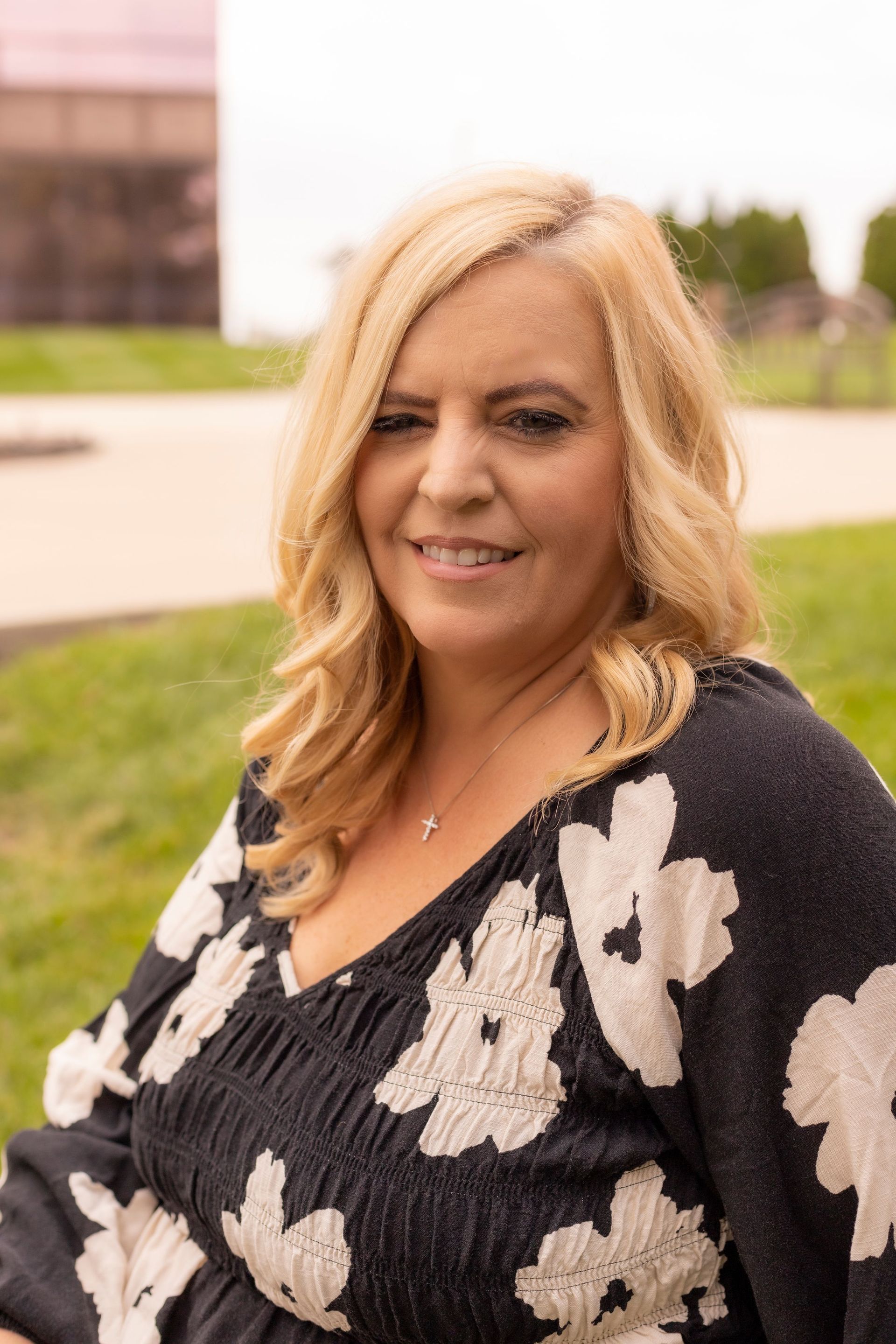 A woman wearing a black and white floral sweater is smiling for the camera.