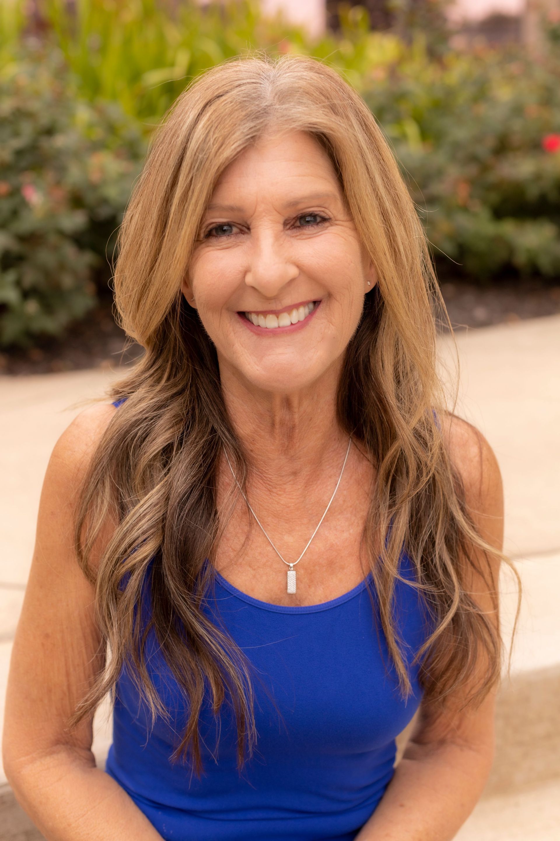 A woman in a blue tank top is smiling for the camera.