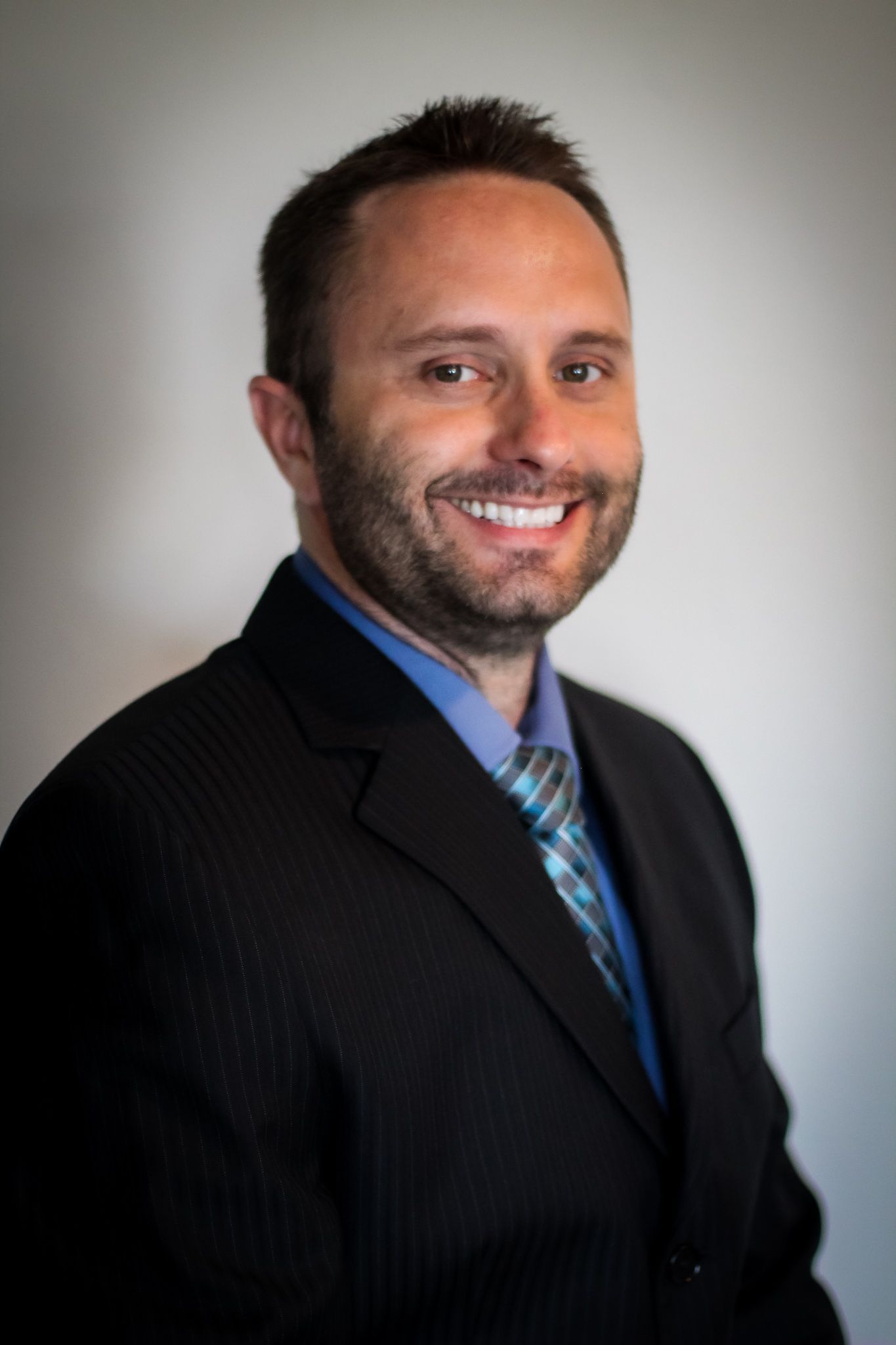 A man in a suit and tie is smiling for the camera
