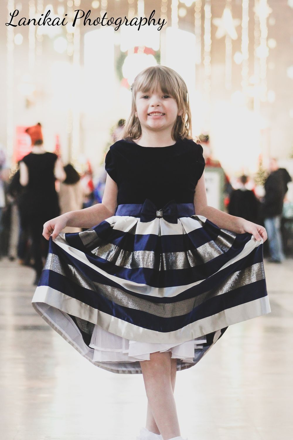 A little girl is wearing a black and blue striped dress