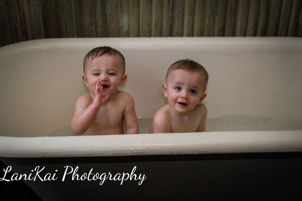Two babies are taking a bath together in a bathtub.