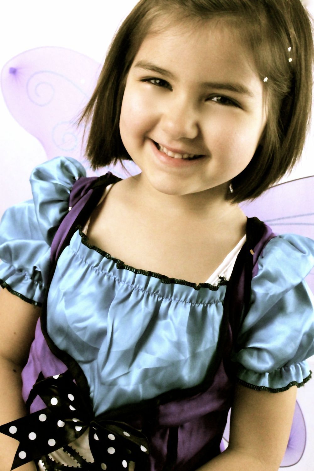 A little girl in a fairy costume is smiling for the camera