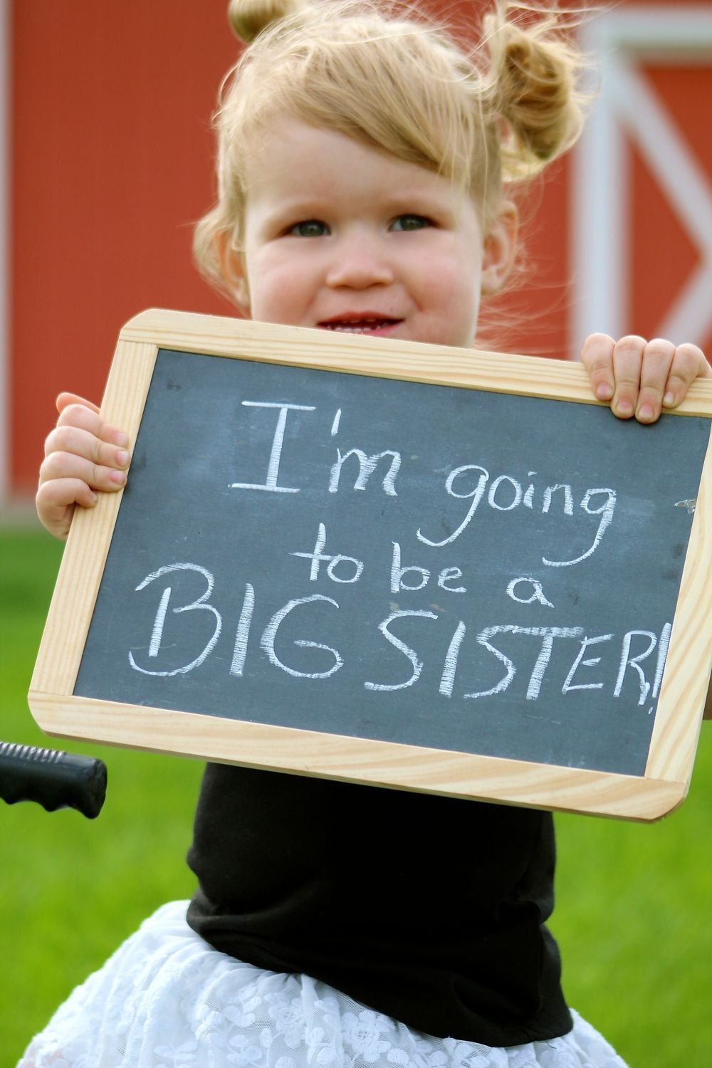 A little girl is holding a chalkboard that says i 'm going to be a big sister