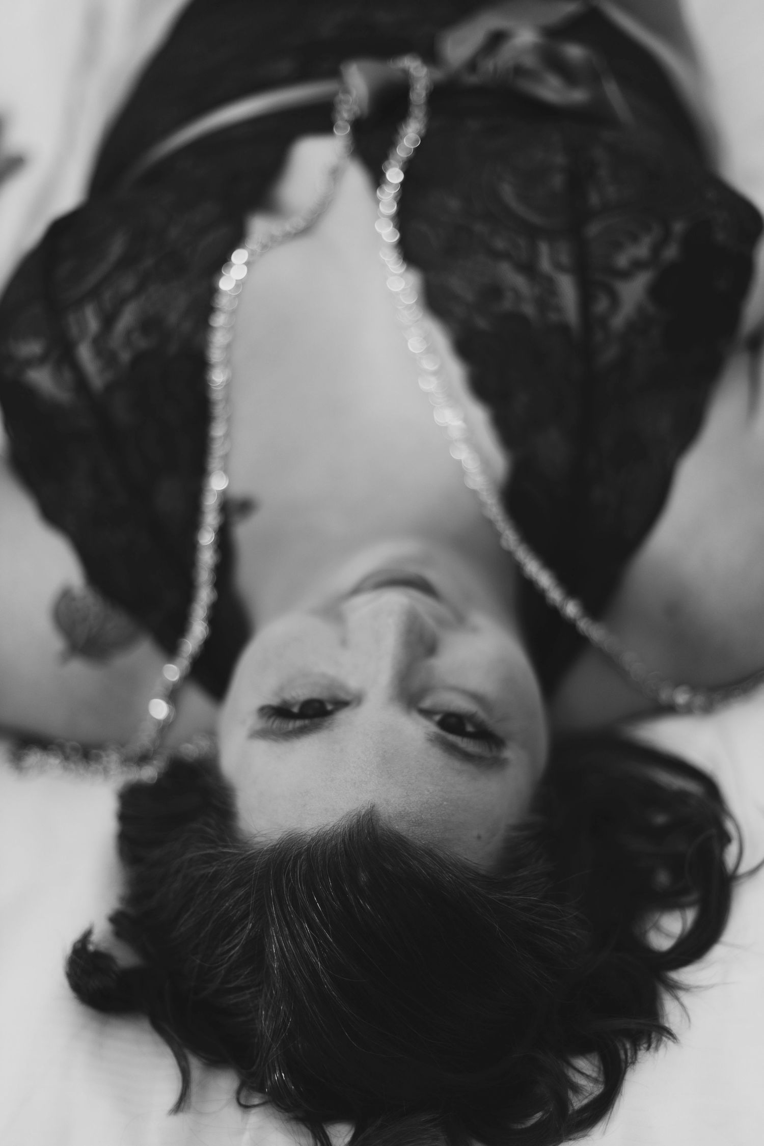 A woman is laying on her back on a bed in a black and white photo.