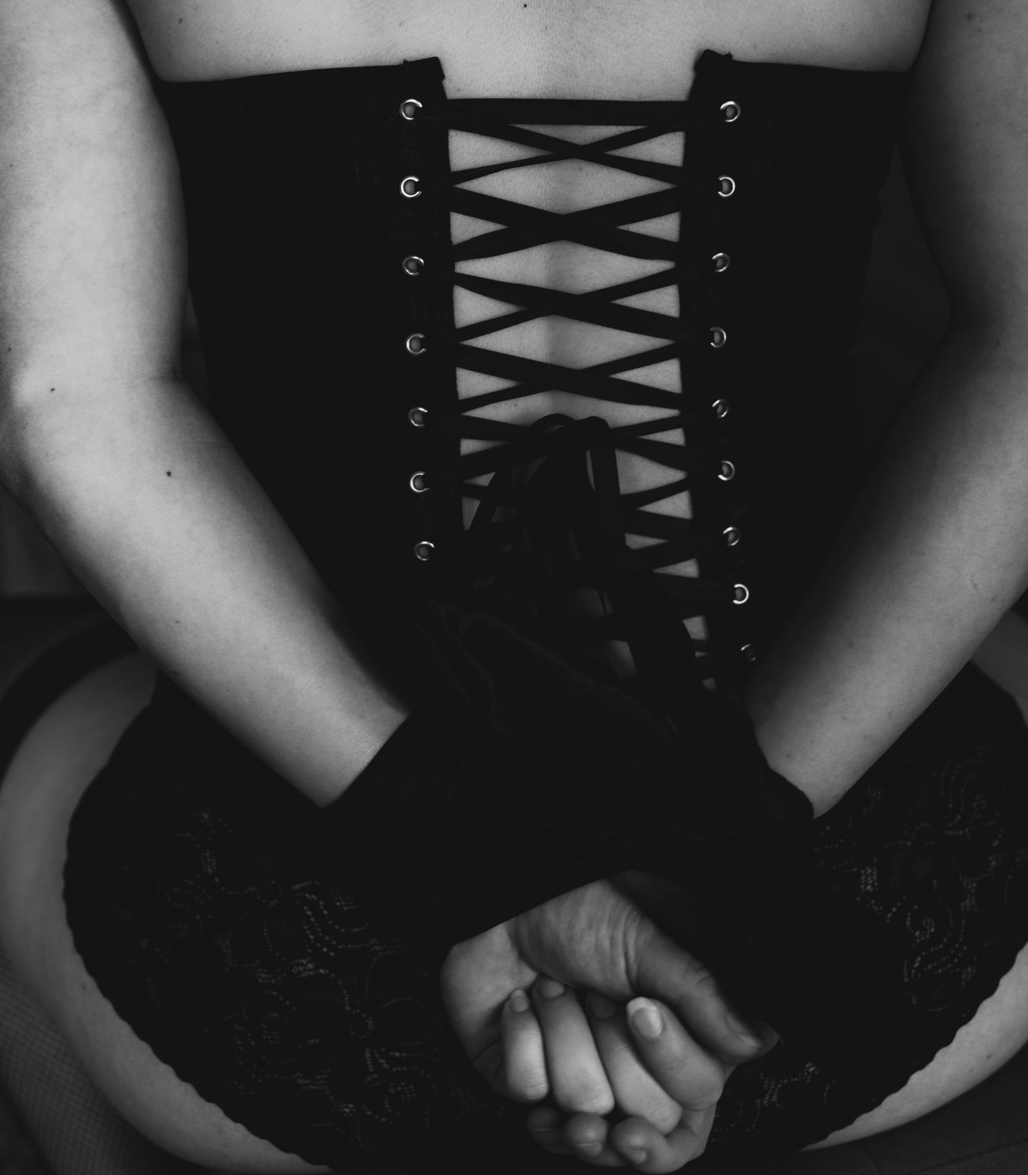 A woman in a corset and gloves has her hands tied behind her back