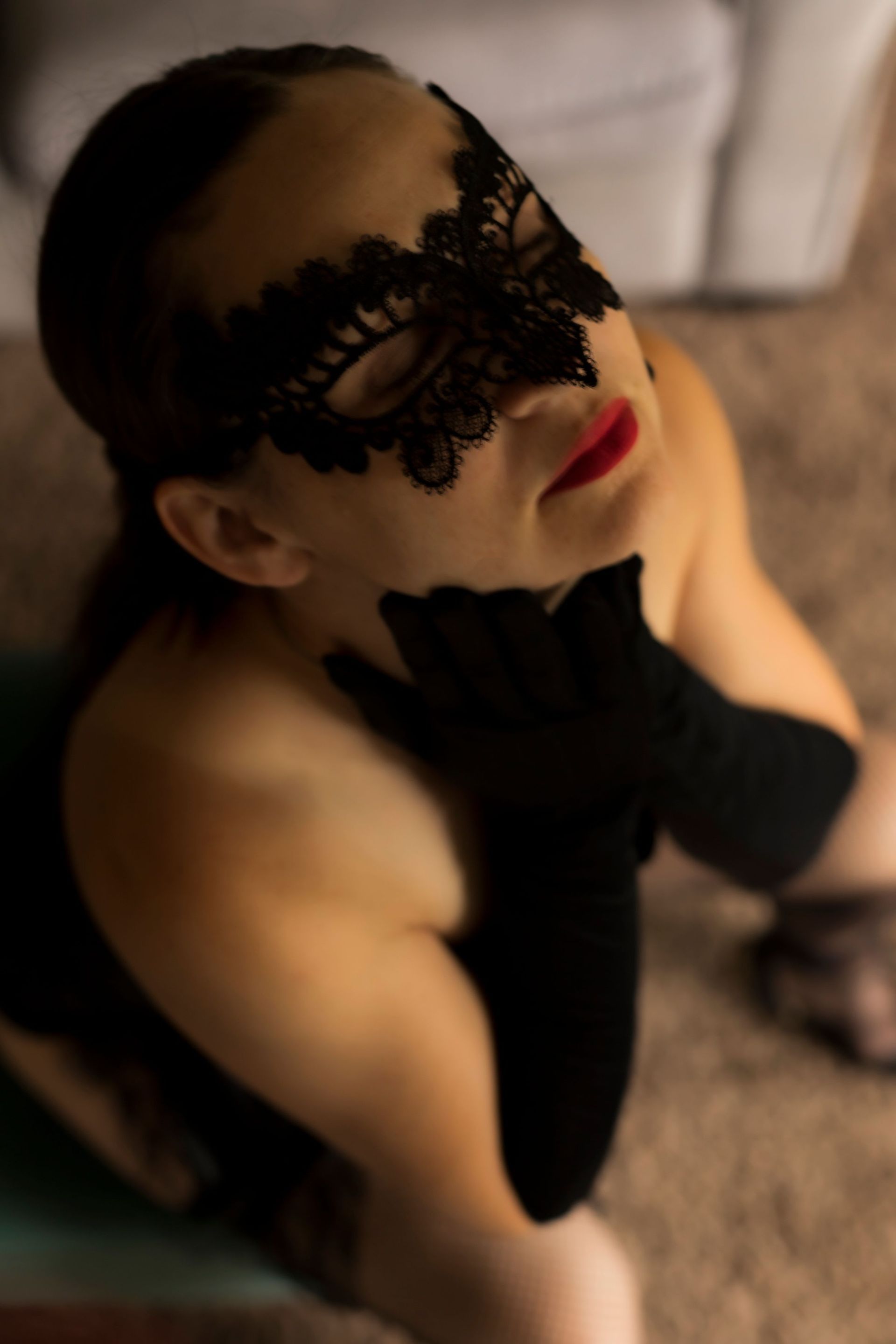 A woman is wearing a black lace mask and black gloves.