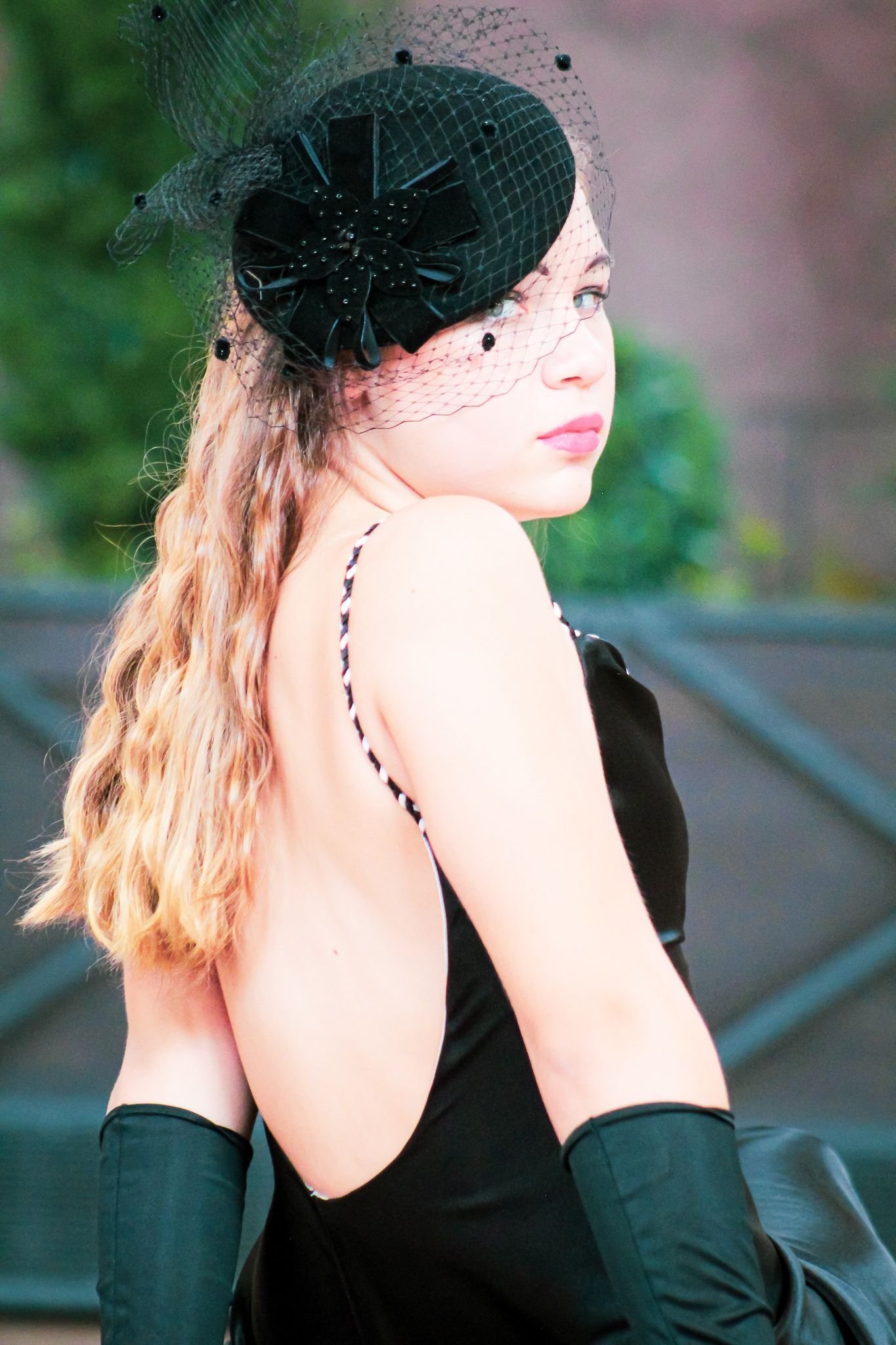 A woman wearing a black hat and gloves looks over her shoulder