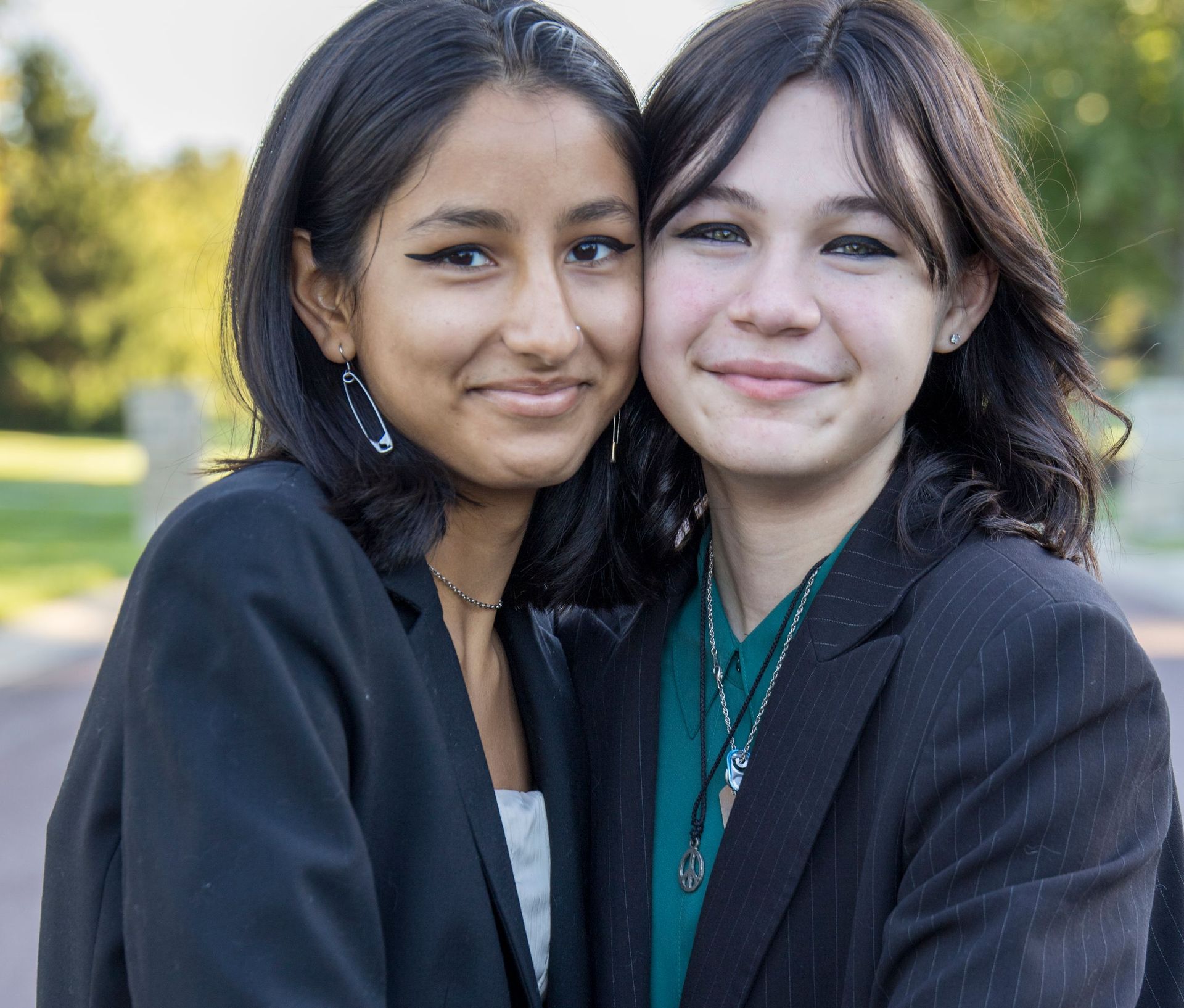 Two women are posing for a picture and one is wearing a green shirt