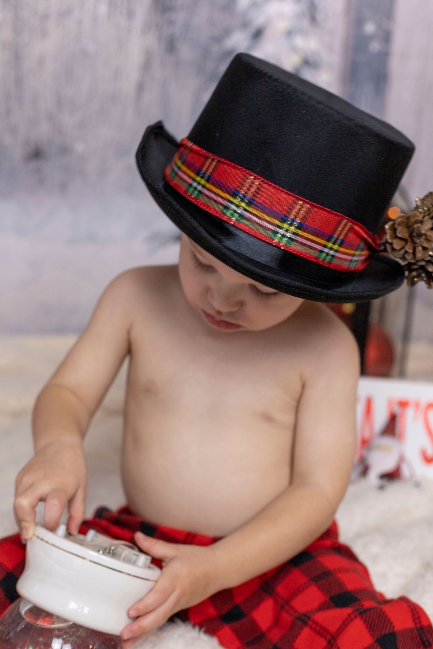 A little boy wearing a top hat is playing with a toy.