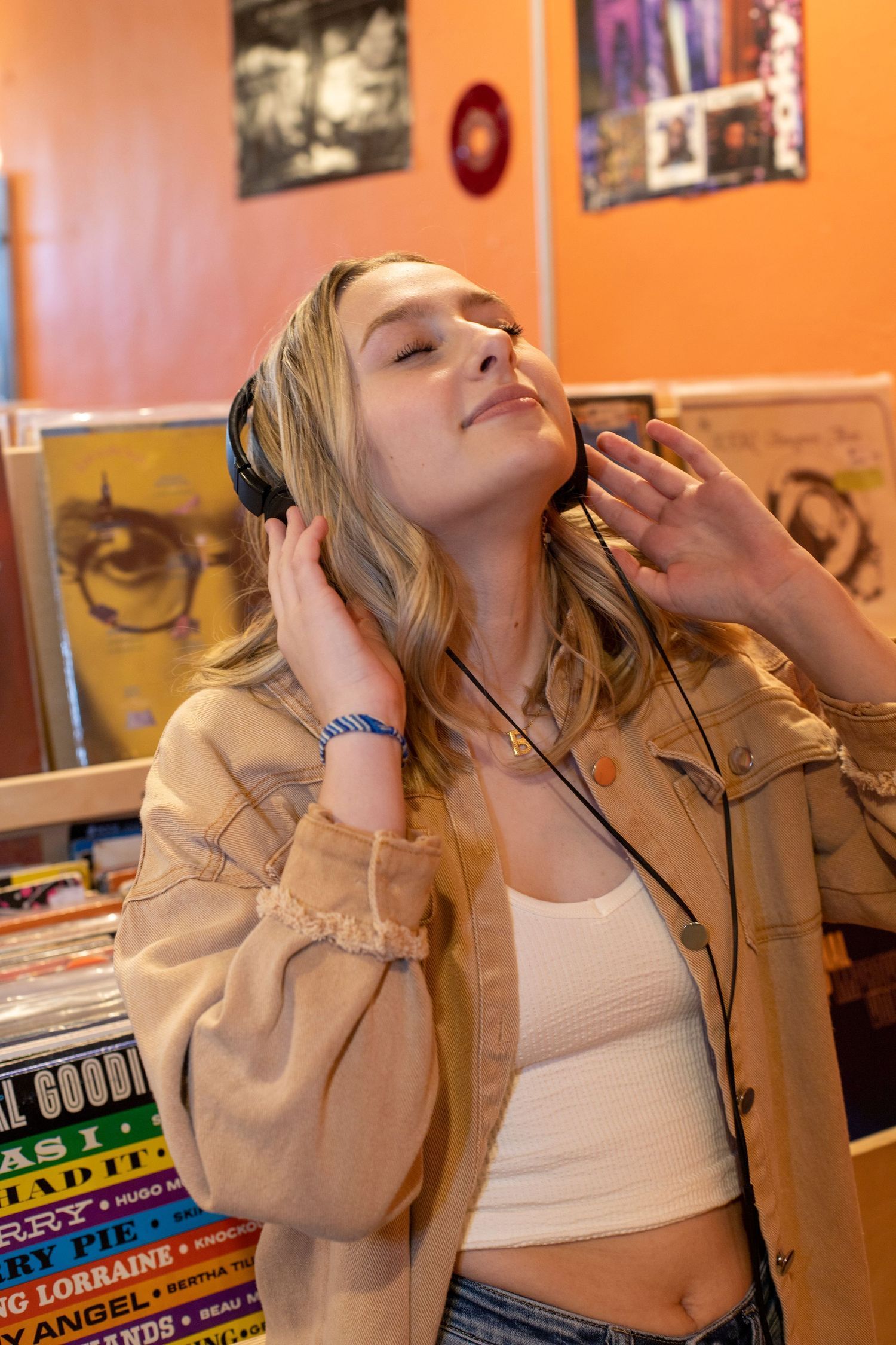 A woman wearing headphones is listening to music in a record store.