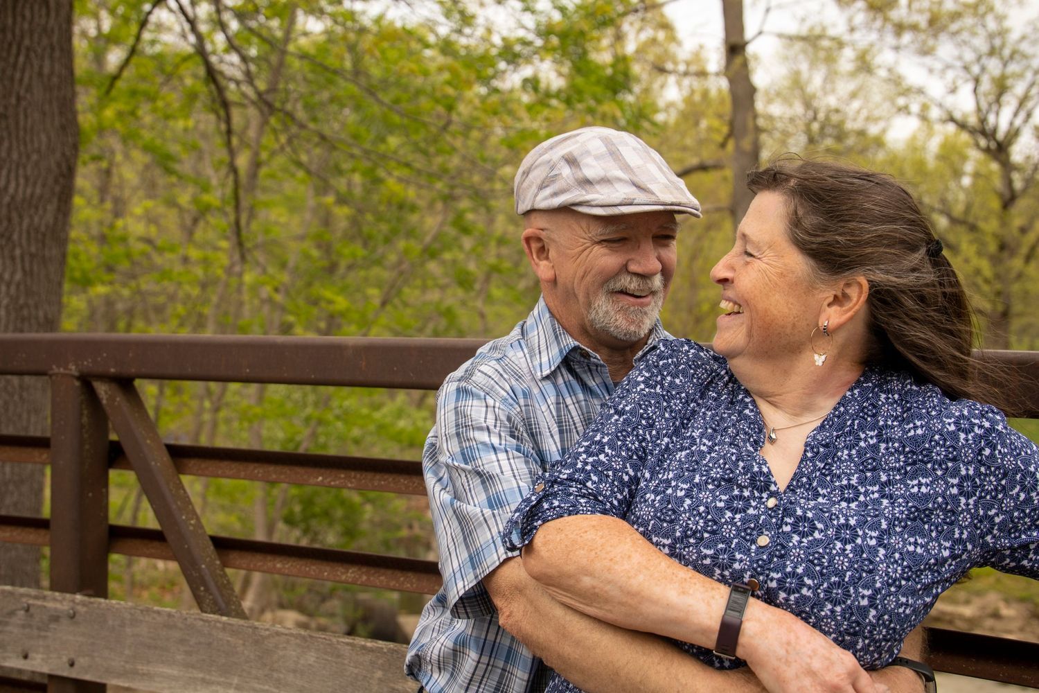 A man and a woman are hugging each other on a bridge.