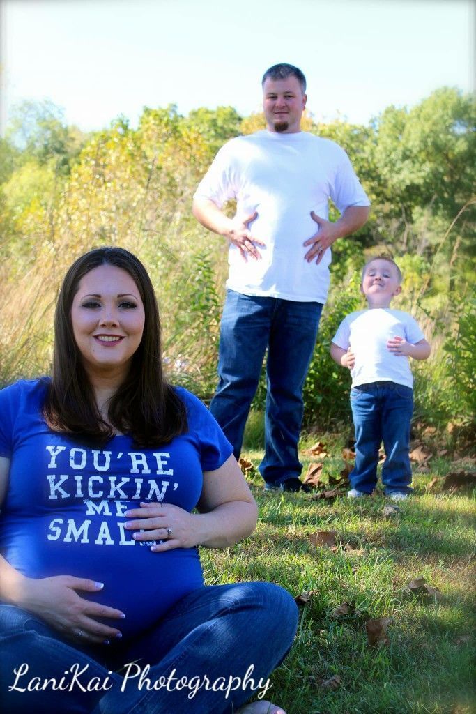 A pregnant woman is wearing a shirt that says you 're kickin ' me small