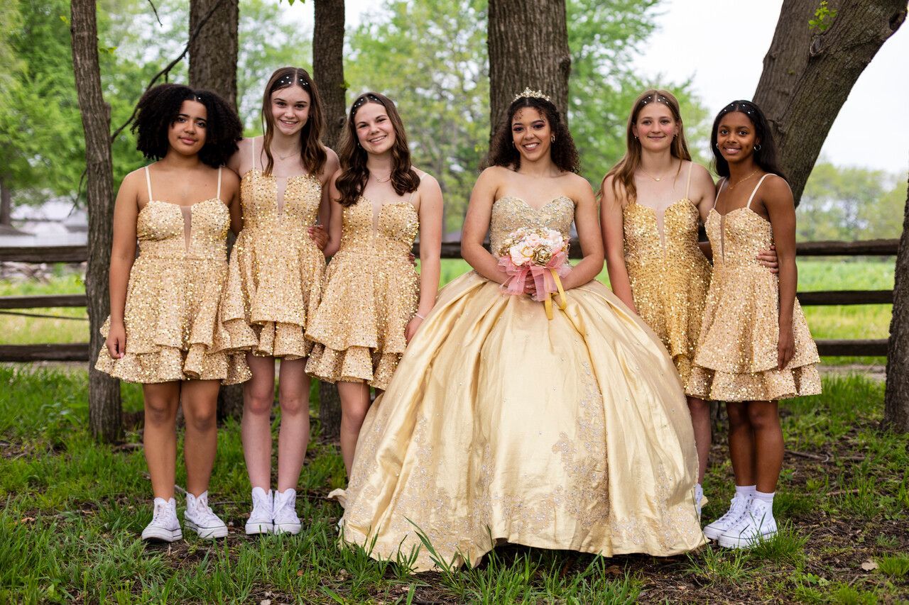 A group of girls in gold dresses are posing for a picture.
