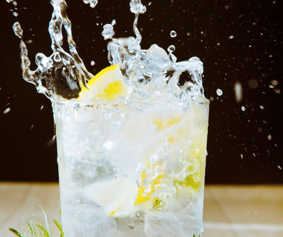 A glass of water with ice and a slice of lemon in it