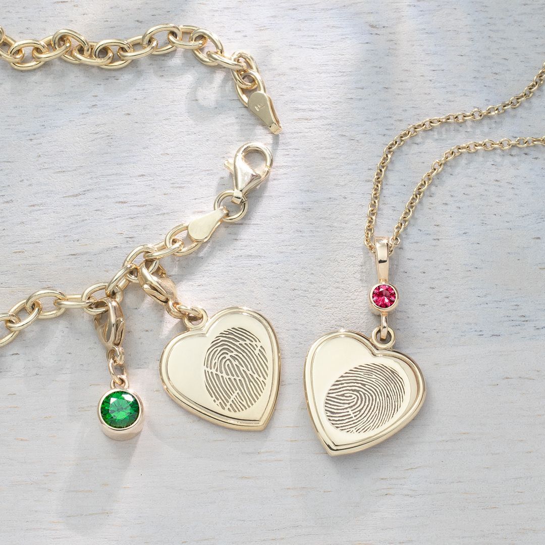 A bracelet and necklace with a heart shaped pendant with a fingerprint on it.