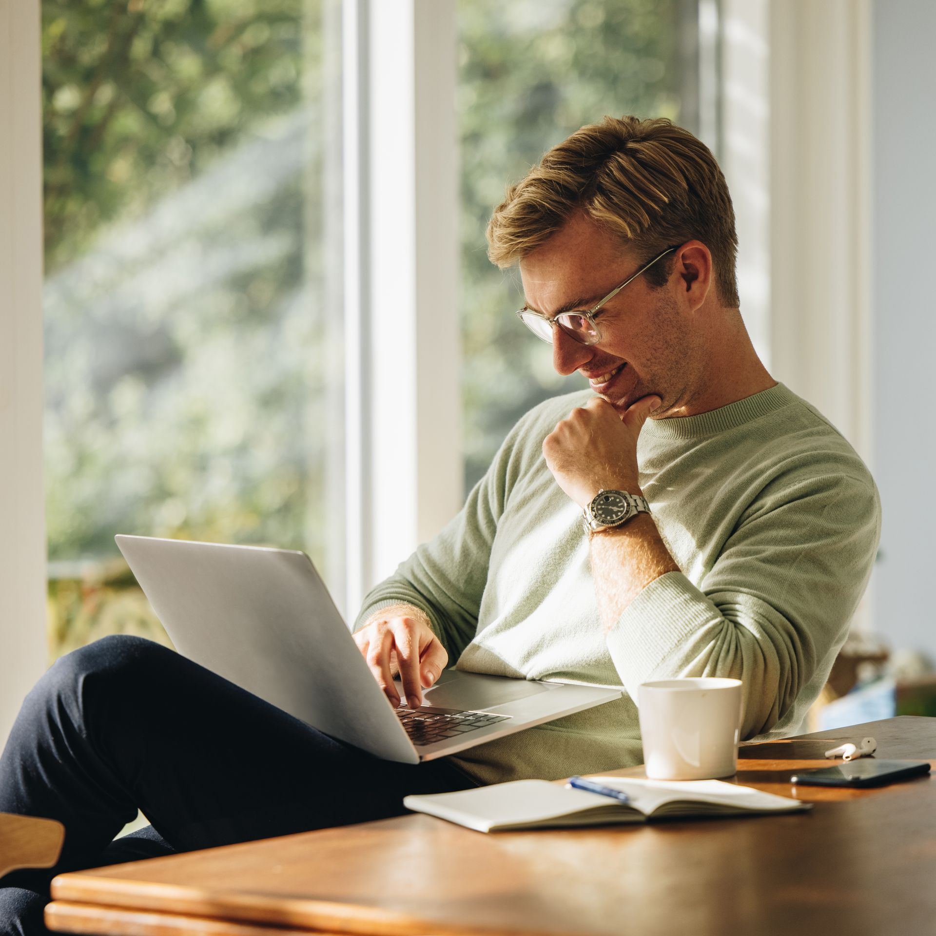 A man is sitting at a table using a laptop computer.
