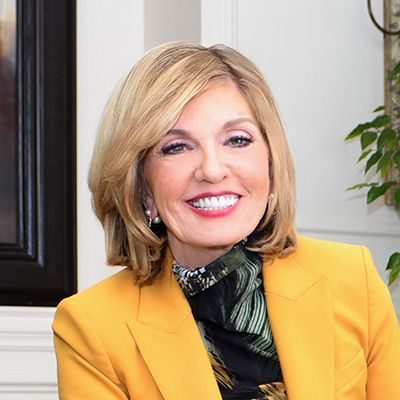 A woman is wearing a yellow jacket and smiling for the camera.