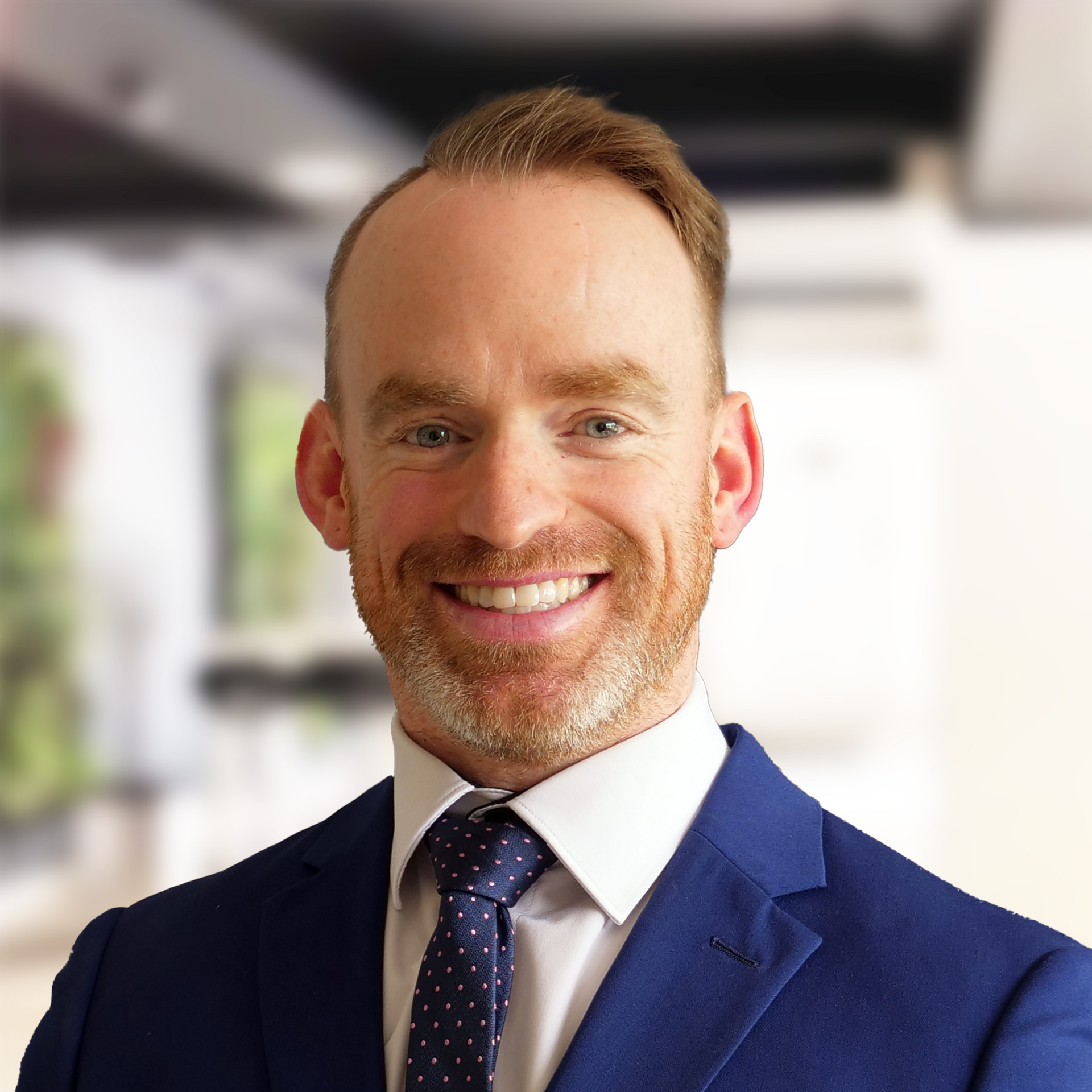 A man in a blue suit and tie is smiling for the camera