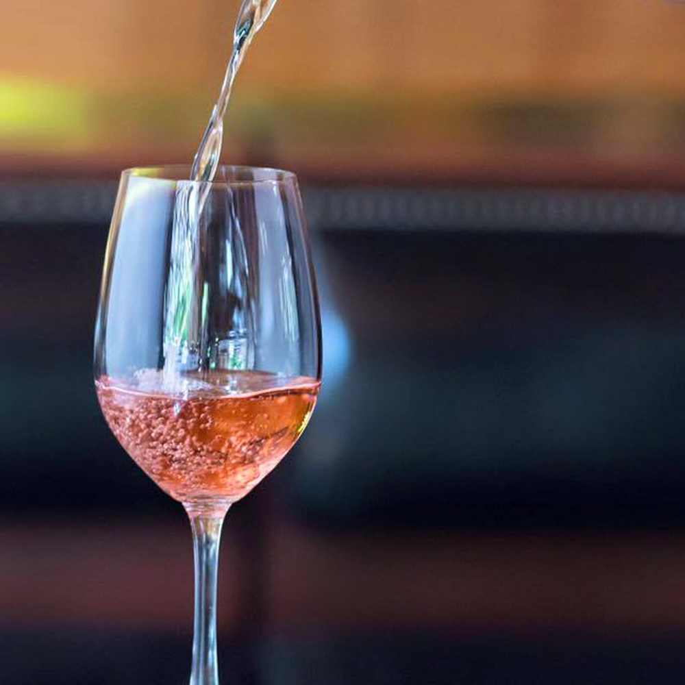 A glass of wine is being poured into a glass on a table.