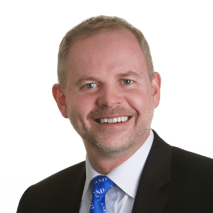 A man in a suit and tie is smiling for the camera