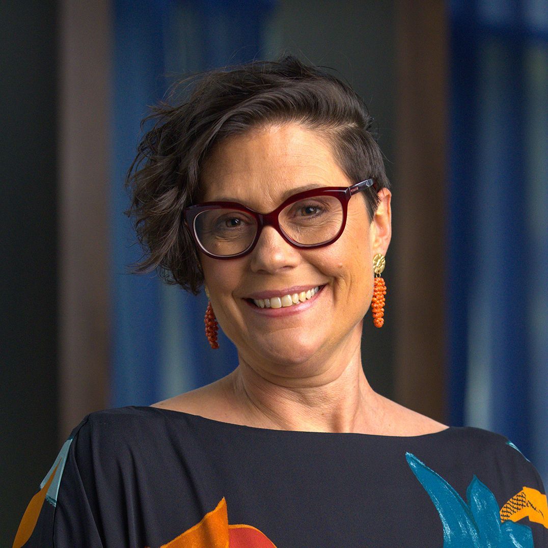 A woman wearing hoop earrings and a black top smiles for the camera
