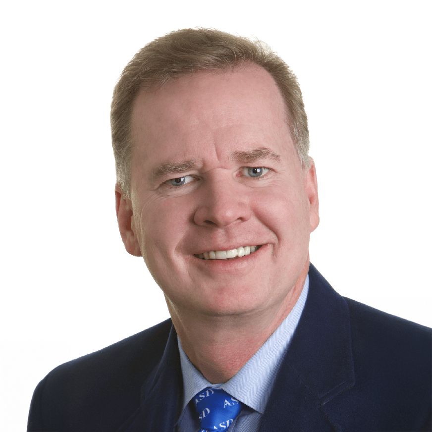 A man in a suit and tie is smiling for the camera