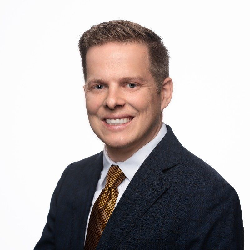 A man in a suit and tie is smiling for the camera