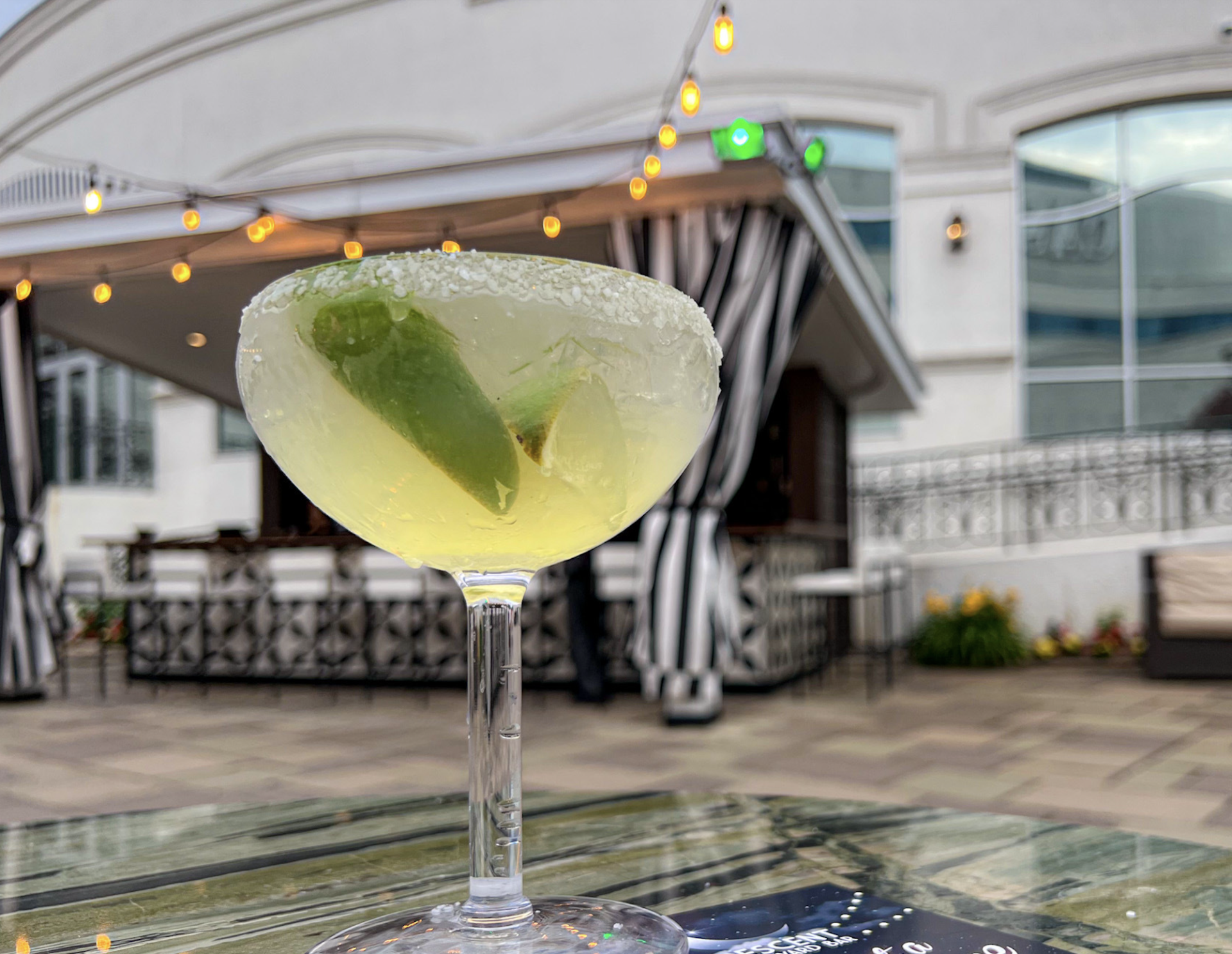 A close up of a margarita in a wine glass on a table.