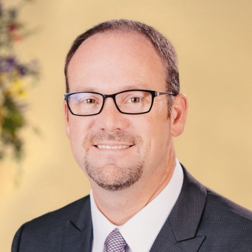A man with a beard is wearing a suit and looking at the camera.
