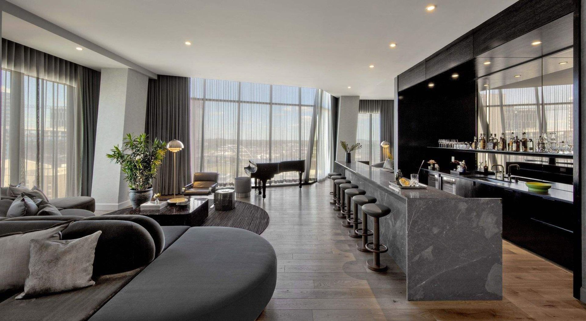 A living room with a couch , piano , and bar.