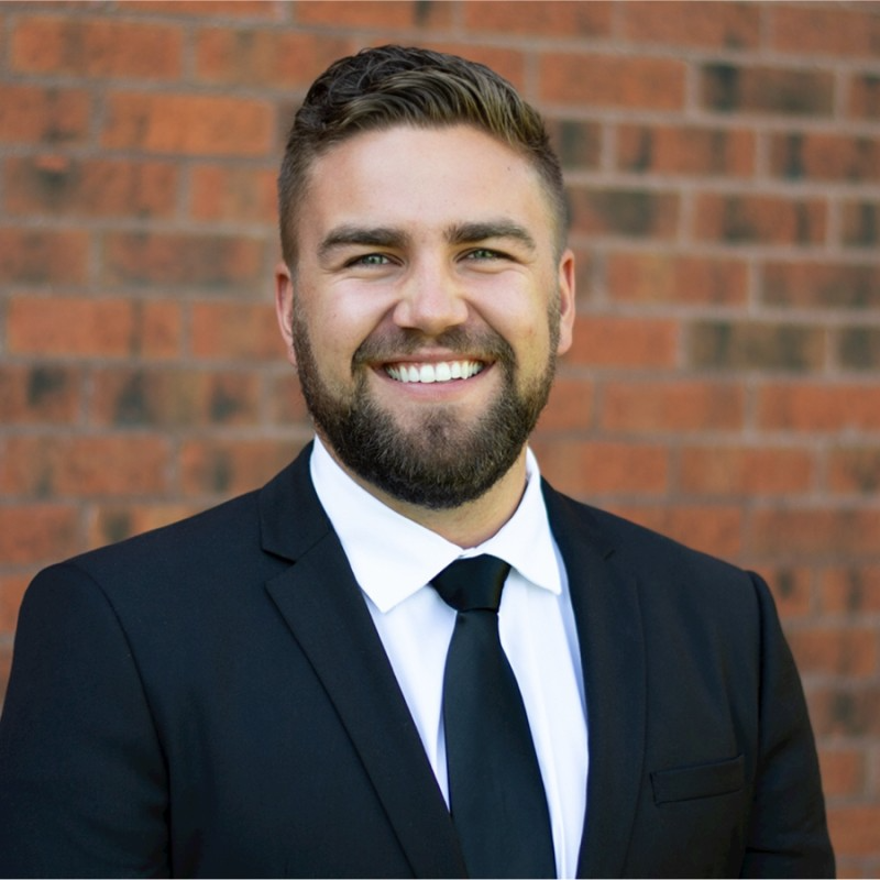 A man with a beard is wearing a suit and looking at the camera.