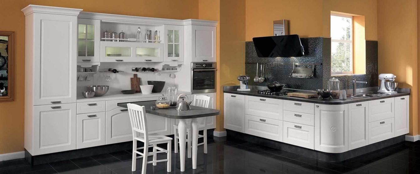 Una cucina con mobili bianchi e ripiani neri