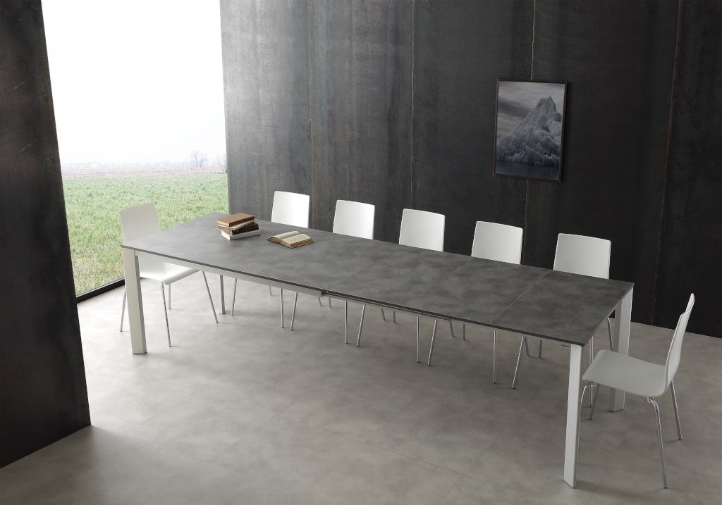 Un lungo tavolo grigio con sedie bianche in una stanza