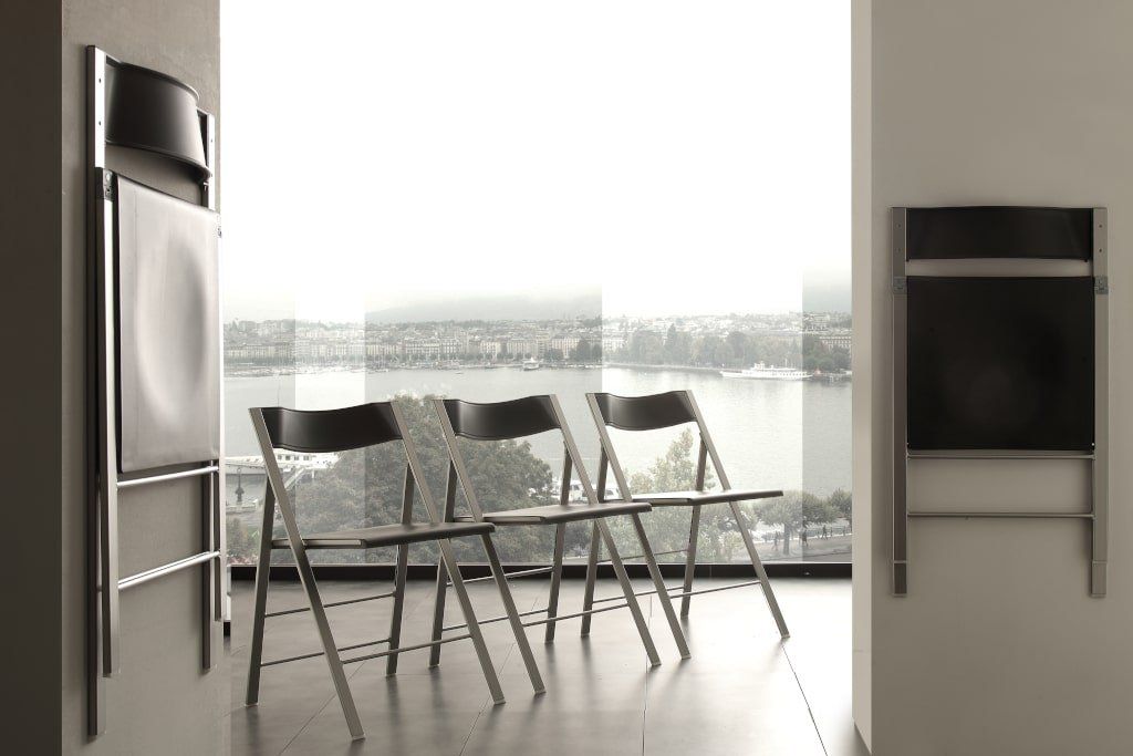 Una fila di sedie pieghevoli è allineata davanti a una finestra.