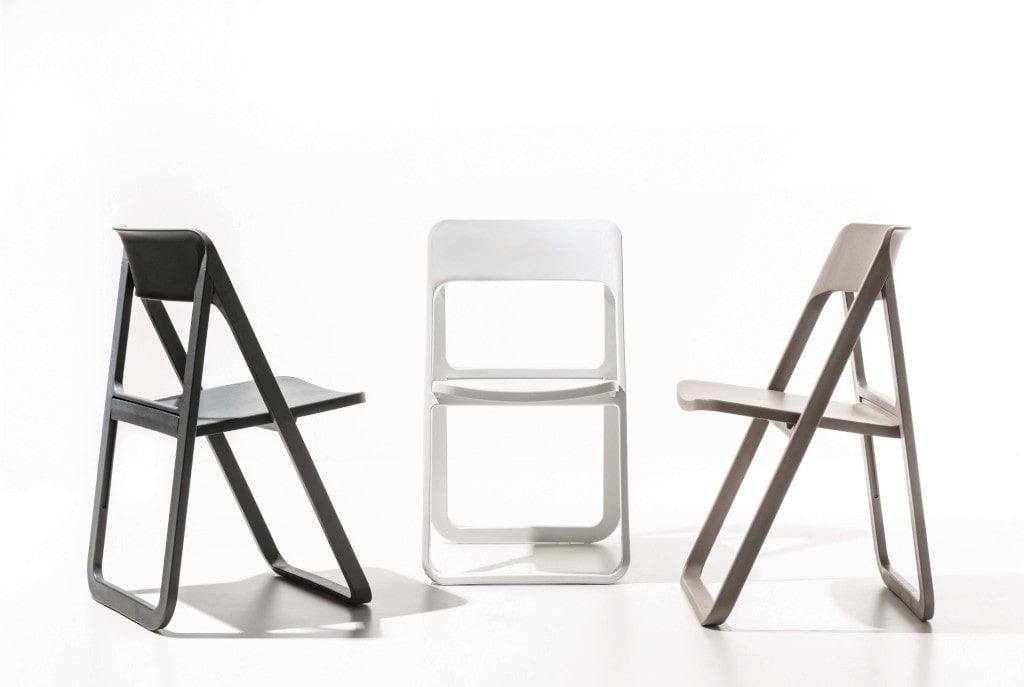 Tre sedie pieghevoli sono appoggiate una accanto all'altra su una superficie bianca.