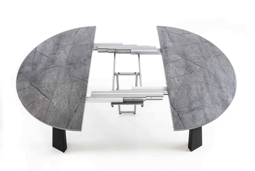 Un tavolo rotondo con il piano grigio e le gambe nere viene allungato.